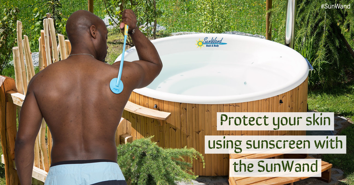A man using a device to put sunscreen on his back next to a hot tub.
