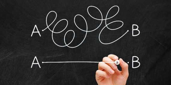 A blackboard with two lines from point A to Point B. One is straight and the other is full of curlicues.